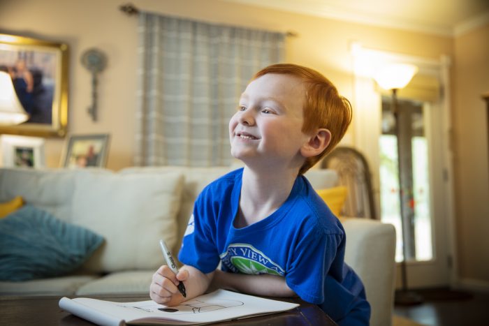 A young boy drawing in a notebook.