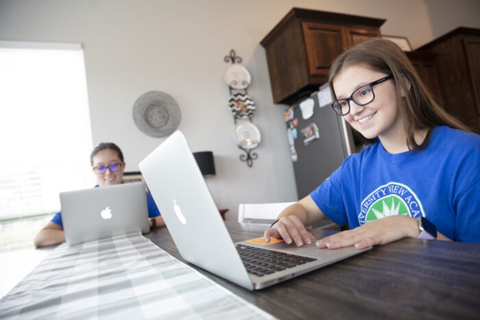 Two middle school girls, doing schoolwork at the table.