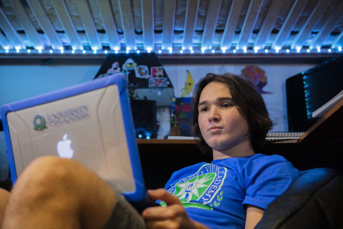 A high school boy, working on his laptop.