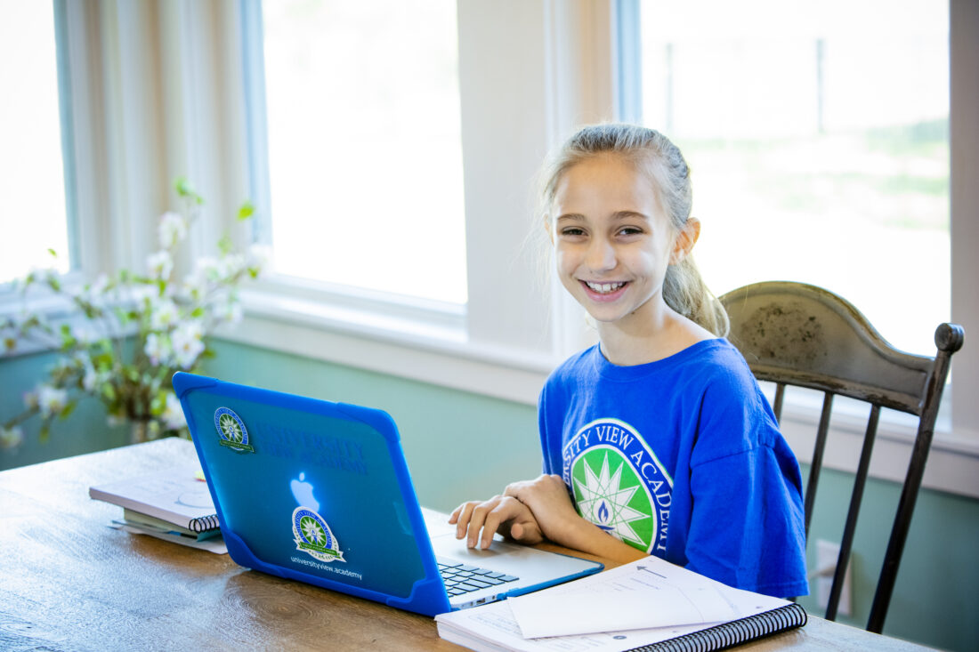 A middle school girl working at her school laptop.