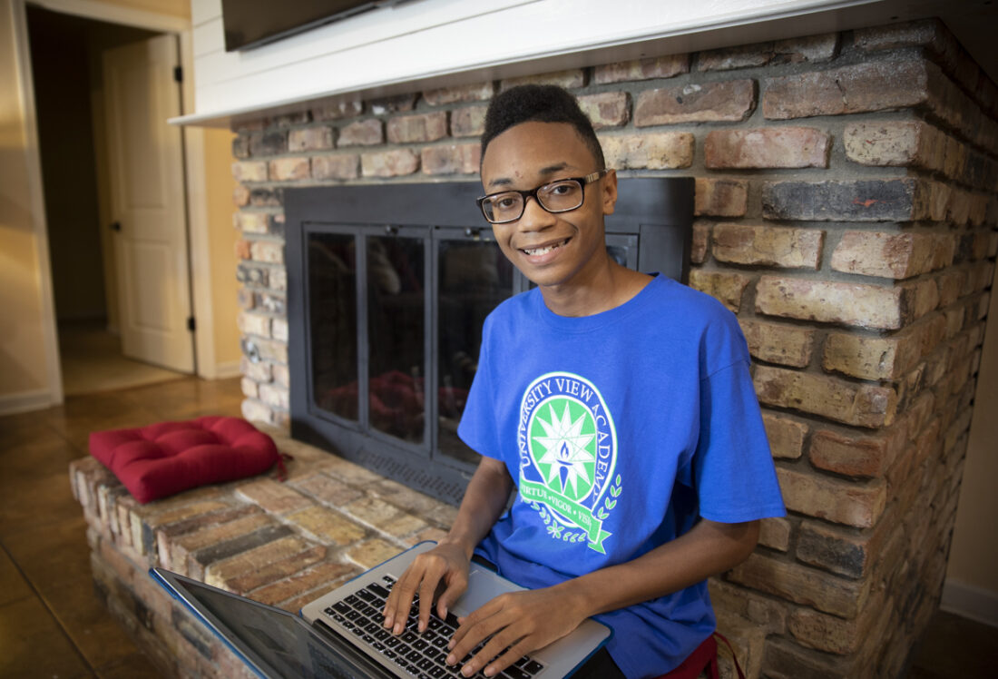 A high school boy, working on his laptop.