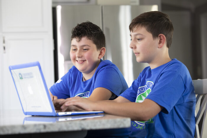 Two middle school boys working on a laptop