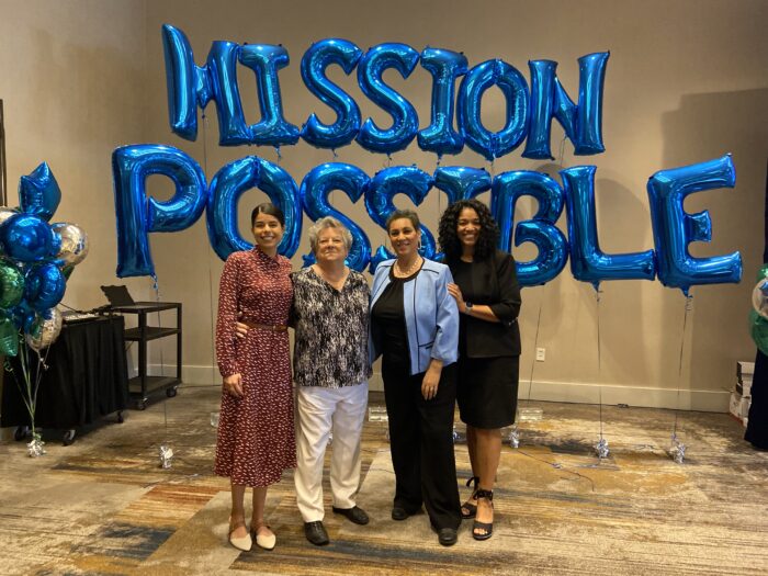 A group of women smiling for the camera in front of balloons.