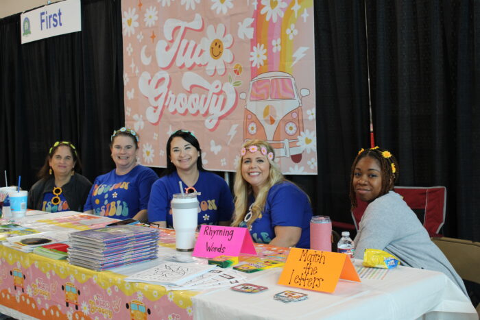 A group of people seated at a display table and smiling for the camera.