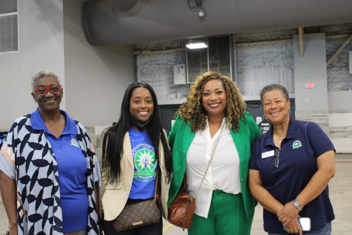 Four people standing arm in arm and smiling for the camera.