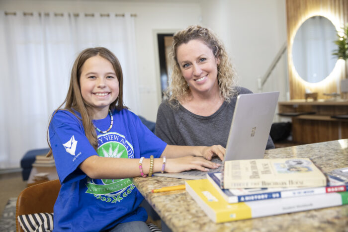 A mother and daughter work together on online school assignments.