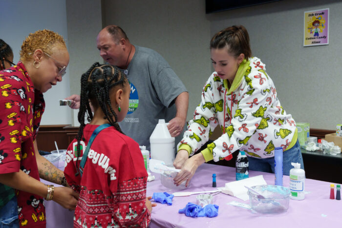 A teacher explains a slime-making activity to a student and mother