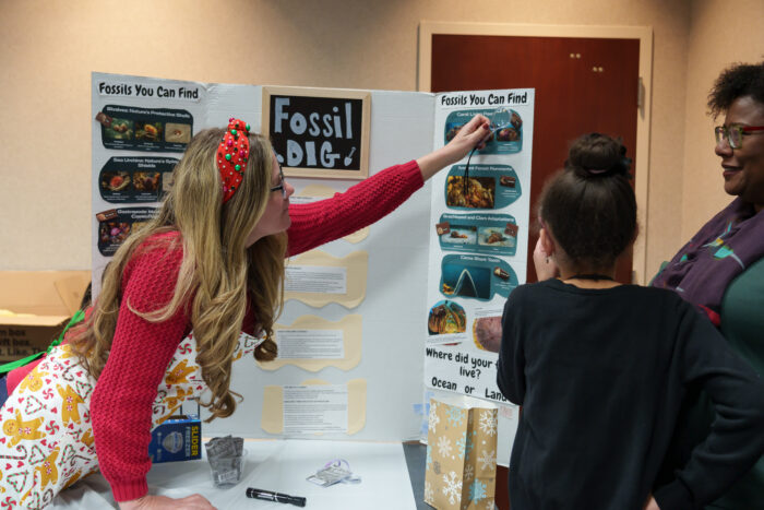 A teacher points out an image on a trifold board to a student