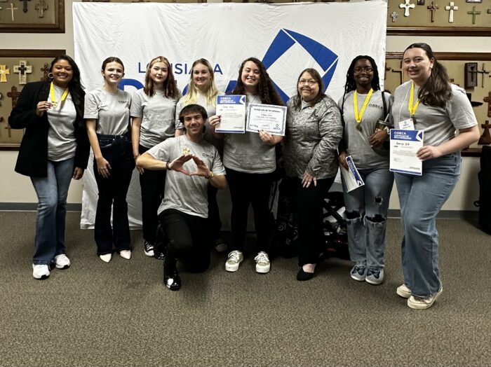 Group photograph of high school DECA chapter officers with advisor Mindy Rose at the Fall Conference. Many of them are holding award certificates.