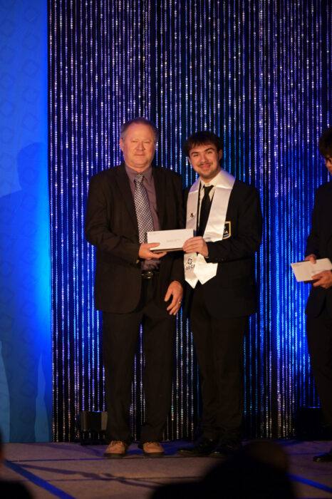 Brock Sykes accepts his scholarship check on a stage.