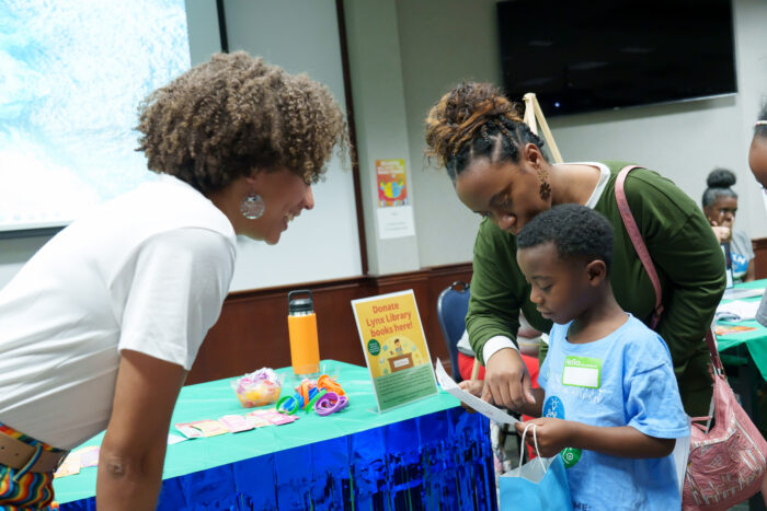 A staff member assists a student and parent at Literacy Day