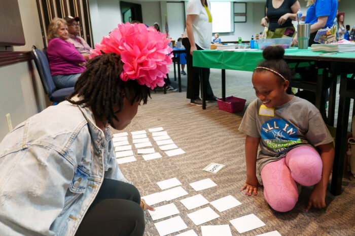 A teacher lays down vocabulary matching game cards with a student at Literacy Day