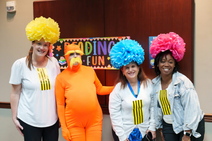 A group of teachers dressed as the Lorax and truffula trees pose for a picture