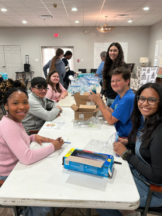NHS students creating cards at a table smile for the camera