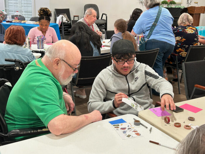 An NHS student and a resident of the senior living community work together to create a card