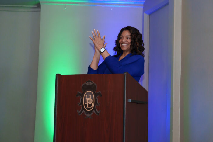 Superintendent Timoll stands behind a podium and claps for students