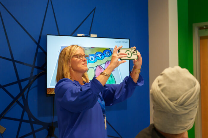 A teacher uses her phone to livestream the exhibit to her students