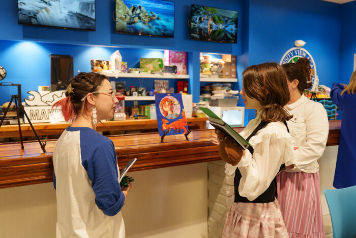 A teacher and a student discuss artwork on display.