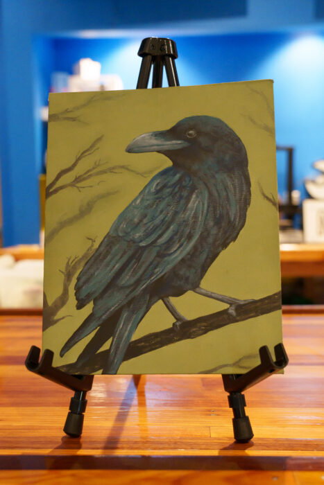 Student painting of a raven perched on a branch.