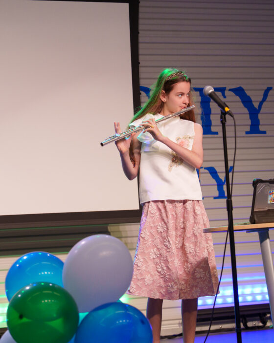 A student plays flute on the Lynx Den stage.