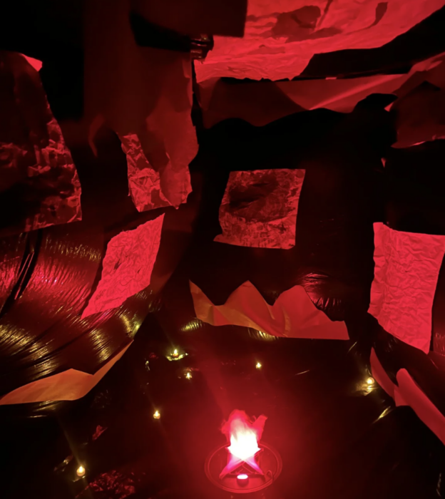 Inflatable cave walk-through experience with student art displayed in red light