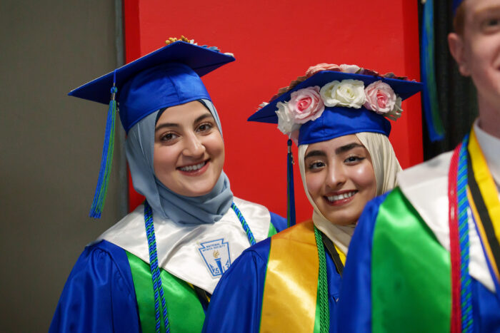 Two students in line to enter the arena smile for the camera.
