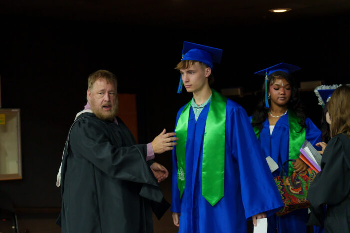A teacher guides students onto the arena floor during the processional.