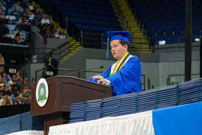 Valedictorian Charles Steele speaks at a podium on stage during graduation.