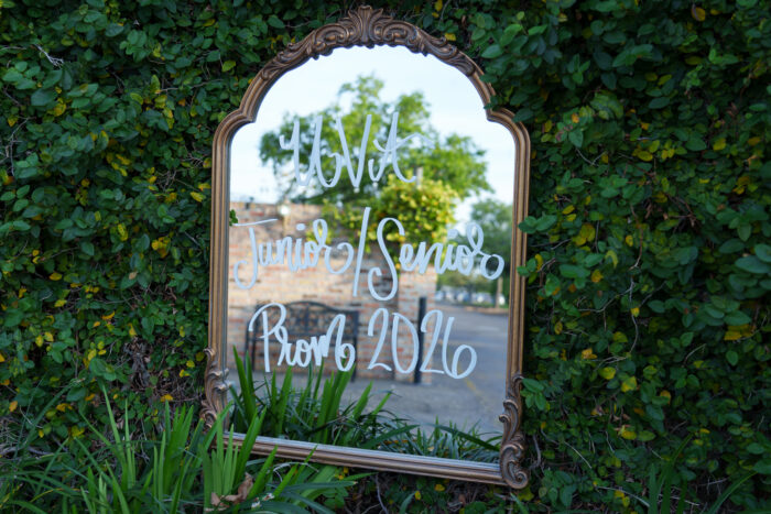 An outdoor decorative mirror reflects greenery with 