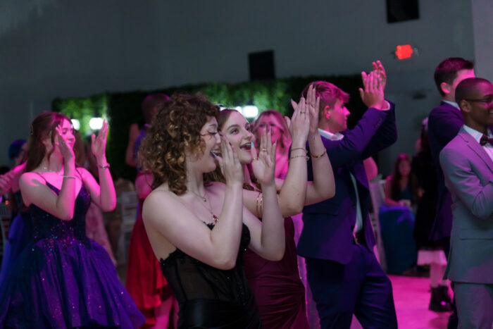 Students clap and laugh on the dance floor.