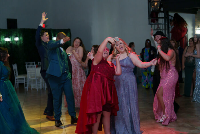 Students dance and take selfies on the dance floor.