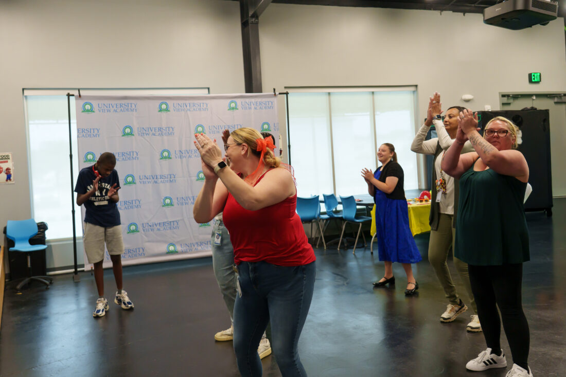 Teachers and students dance and clap.