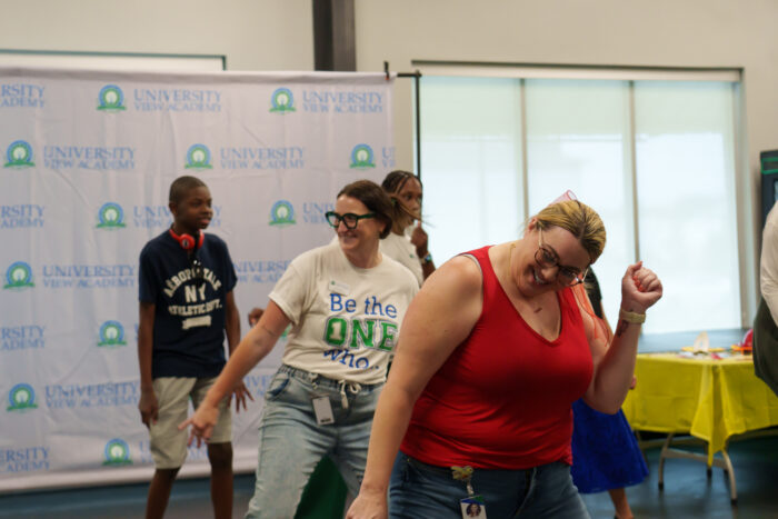 Teachers and students dance and smile.
