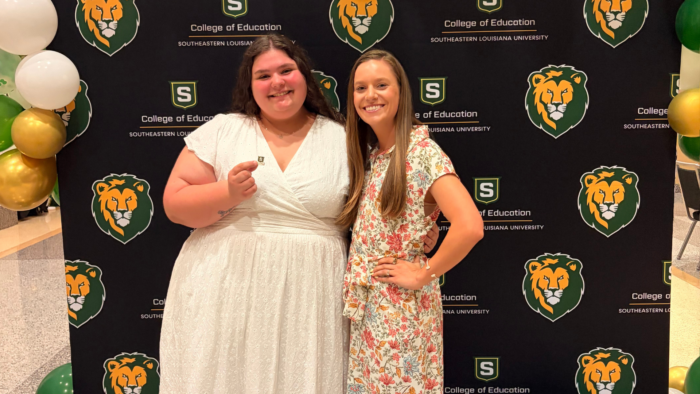 Avery Barnett and her mentor teacher smile in front of a Southeastern Louisiana University College of Education backdrop with balloons.