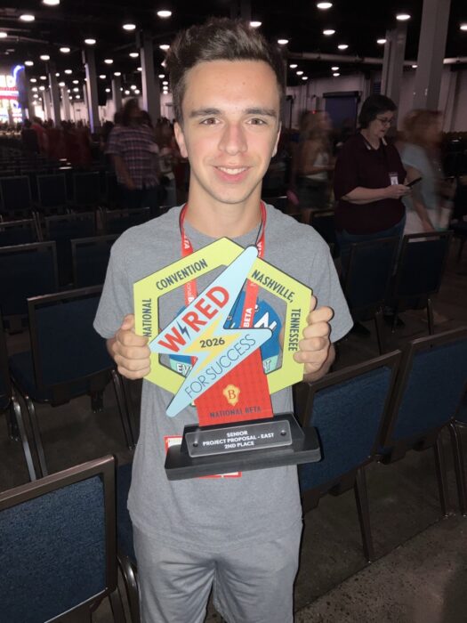 A student holds a vibrant trophy at a convention.