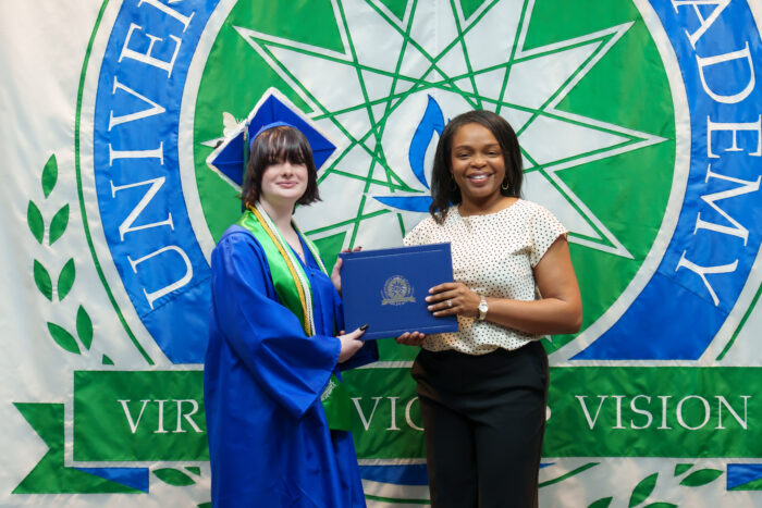 A graduate receives a diploma from Principal Watson.