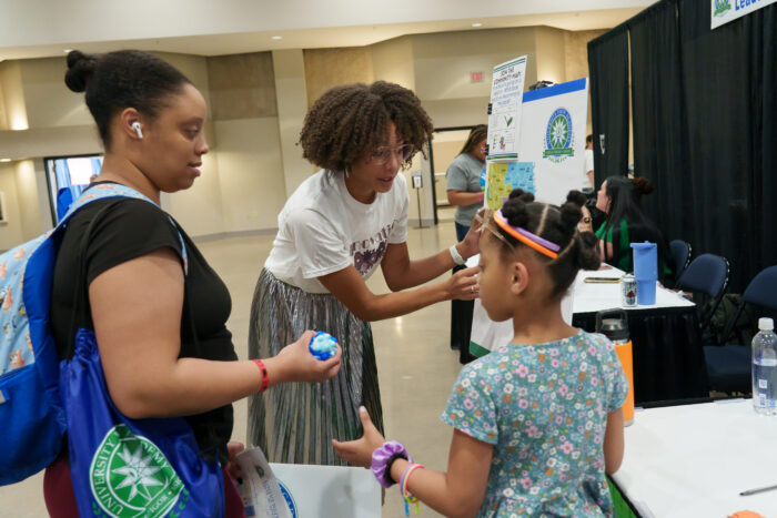 A student plays a game at a table, assisted by a staff member.