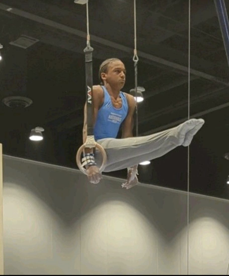 Josiah J holds an L-sit on gymnastics rings.