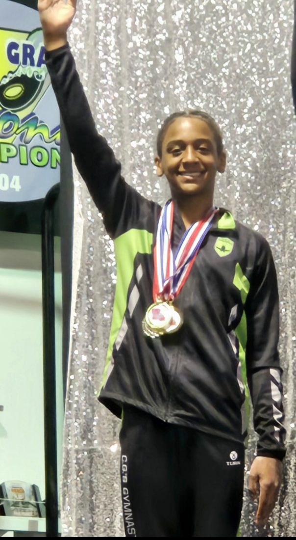 Josiah Jordan stands on a podium with medals and one arm raised.
