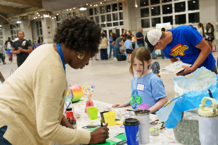 A student completes an activity at a table while a teacher watches.