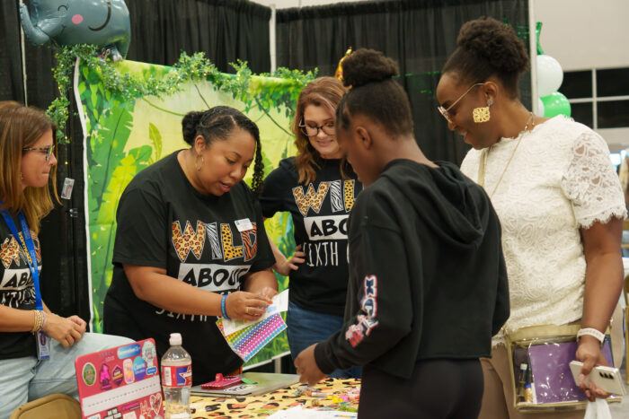 A group of teachers greet a family at a safari-themed table.
