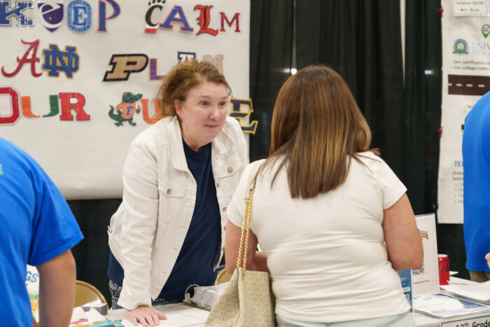 A counselor talks with a visitor at her table.