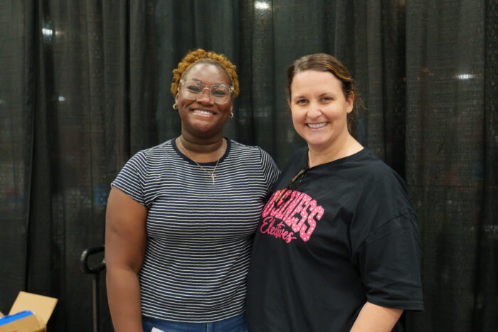 A student and a teacher smile and pose for the camera.