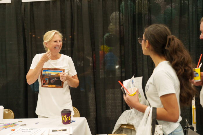 A teacher smiles at a student visiting her table.