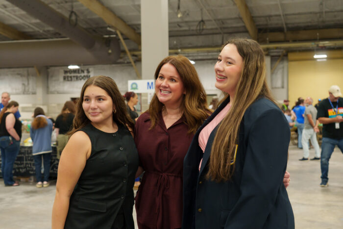 Two students pose for a picture with a teacher.