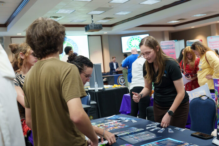 A recruiter shows items on her table to a family.