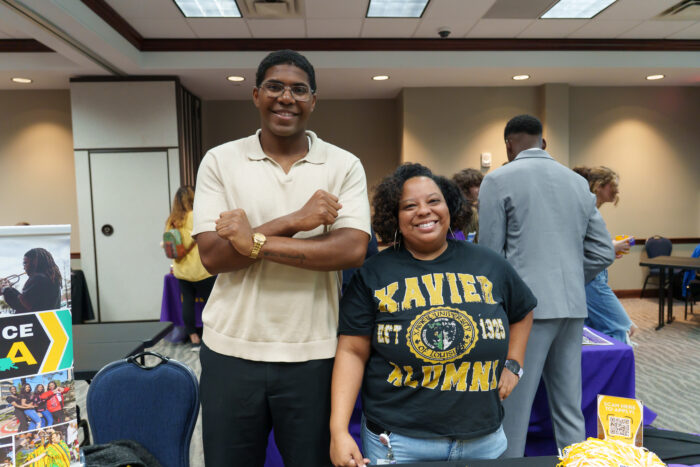 A teacher in a Xavier University t-shirt poses for a picture with a Xavier recruiter.
