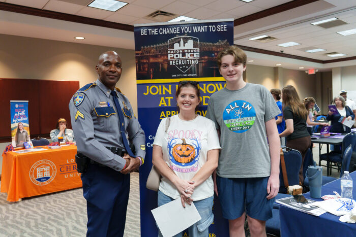 A student and his mother pose for a picture with a recruiter from the Baton Rouge Police Department.